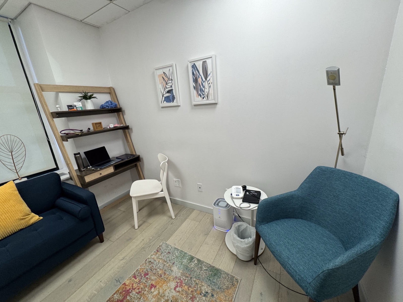 Consultation room at Robin Warner Neurology — blue armchair, navy couch, and ladder shelf in the Midtown East office
